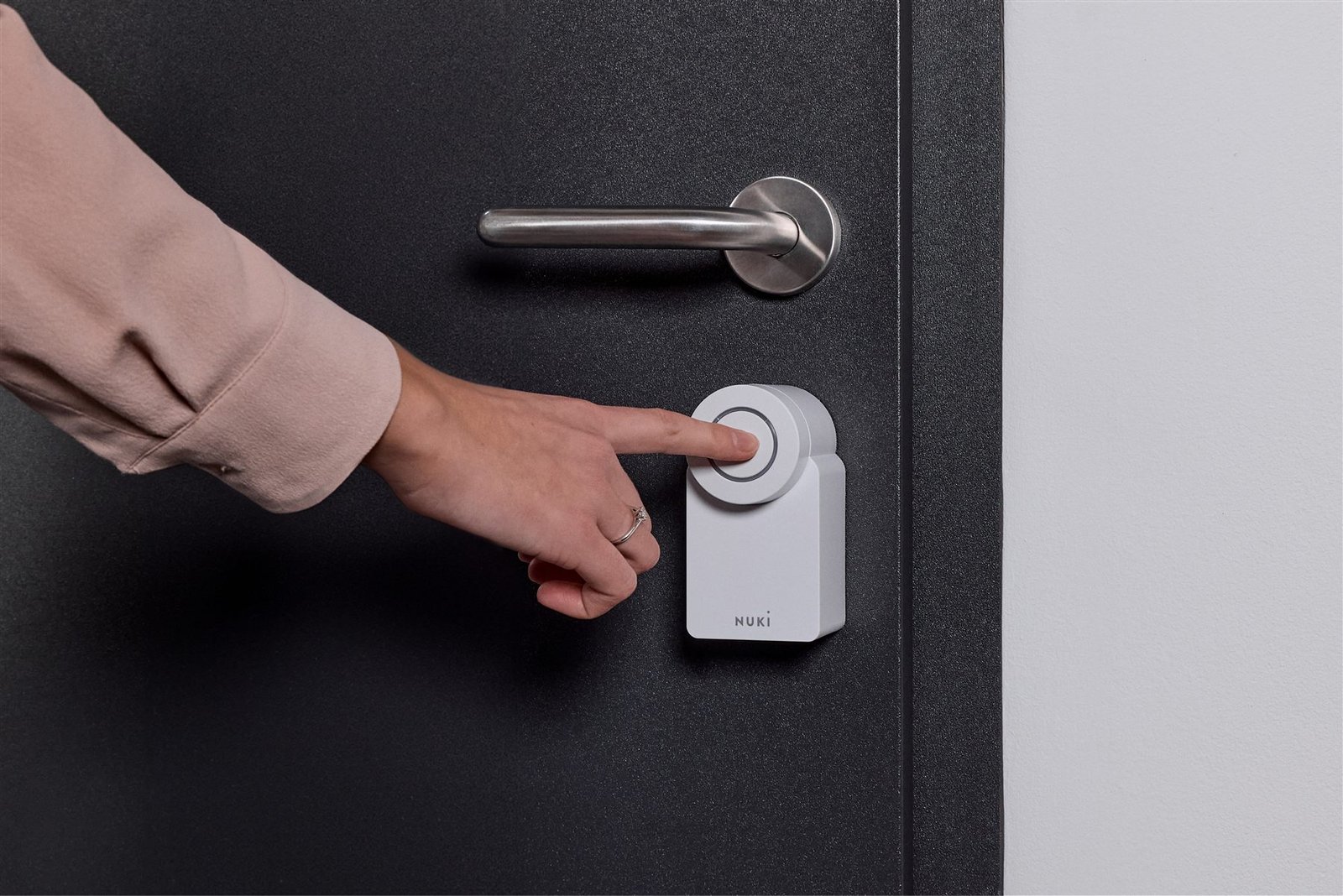 A hand pressing the Nuki smart lock button inside the house